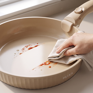 Wycieranie ściereczką ceramicznej powłoki patelni HU.KA Nestio po smażeniu